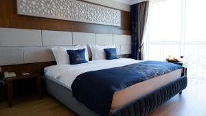 a hotel room with a large bed with blue pillows at BM HOTEL City in Samsun