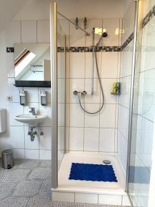 y baño con ducha y alfombra azul. en Remedium Appartements en Vlotho