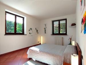 a bedroom with a bed and two windows at Lo Spazio Creativo in Romano Canavese