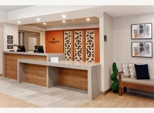 an office lobby with a reception desk and a chair at Candlewood Suites Detroit Sterling Heights by IHG in Waldenburg +17 photos