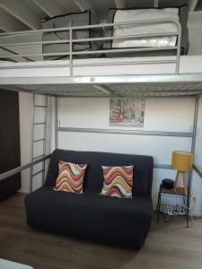 ein Sofa in einem Zimmer mit einem Hochbett in der Unterkunft Studio meublé 1 pièce entièrement équipé sans cloisons séparatives in Chavagnes-en-Paillers