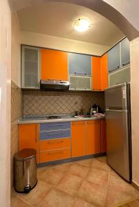 a kitchen with orange cabinets and a stainless steel refrigerator at Seashell Hideaway Apartment in Pržno