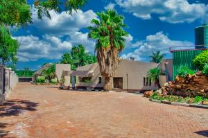 un bâtiment avec deux palmiers dans une allée dans l'établissement Riverstone Guest Lodge, à Harare