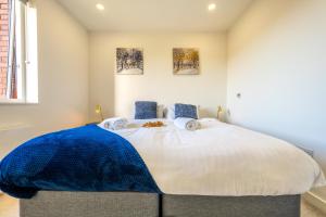 a bedroom with a large bed with a blue blanket on it at Luxury 1 Bedroom serviced apartment with Roof terrace & Gym in Stevenage