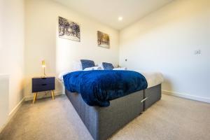 a bedroom with a bed with a blue blanket on it at Luxury 1 Bedroom serviced apartment with Roof terrace & Gym in Stevenage