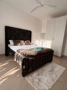 a bedroom with a large bed with a black headboard at Haller Park Apartments Pacific Bamburi in Mombasa