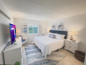 a bedroom with a bed and a flat screen tv at Coastal condo with beachfront views and pool access! in New Smyrna Beach