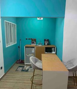 cocina con paredes azules, mesa y sillas en Sublime petite maison à Koira Kano en Niamey