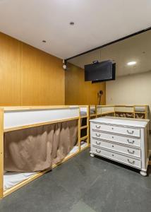 um quarto com uma televisão e uma cómoda branca em Hostel & cia no Porto