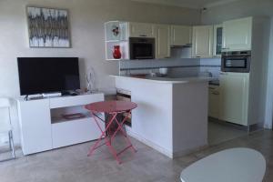 a kitchen with white cabinets and a table and a tv at Cozy cocoon with balcony close to the sea in Cannes