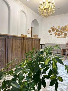 roślina doniczkowa w holu z żyrandolem w obiekcie MUNIS Hotel lyabi houz w mieście Buchara