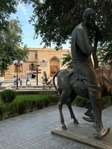 a statue of a man riding a horse in front of a building at MUNIS Hotel lyabi houz in Bukhara