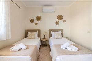 2 aparte bedden in een kamer met witte muren bij Villa Dimitra - Amazing sea view in Póros
