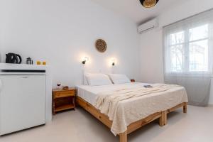 a white bedroom with a bed and a window at Naxos Beachwalk Rooms in Naxos Chora