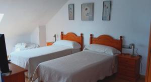 1 dormitorio con 2 camas y TV en Pension Doña Lubina, en Finisterre