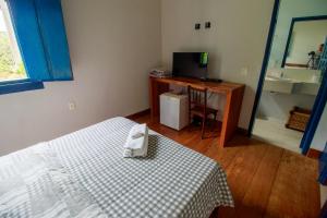 a bedroom with a bed and a desk with a television at Hotel Fazenda Palmeiras in Rio Casca