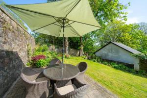 a table with an umbrella in a garden at Binrock Lodge in Dundee