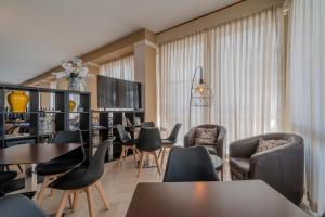 Hotel Mia في ريميني: غرفة معيشة مع طاولات وكراسي وتلفزيون