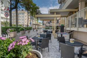 Hotel Mia في ريميني: فناء به طاولات وكراسي وزهور