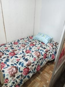 - un lit avec une couette à fleurs et un oreiller dans l'établissement POSADA CHABELITA, à Lima