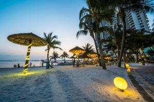 a sandy beach with palm trees and a building at Royal Strand, Country Garden Danga Bay, Johor Bahru, Johor in Johor Bahru