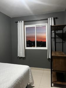 un dormitorio con una cama y una ventana en Apartamento no último andar + vaga de garagem, en Cascavel
