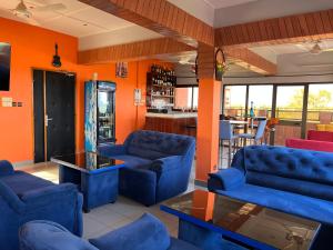 AG HOTEL Ouaga في واغادوغو: غرفة معيشة مع الأرائك الزرقاء والجدران البرتقالية
