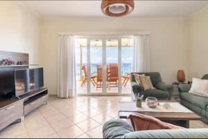 een woonkamer met een bank en een tv bij Villa Dimitra - Amazing sea view in Póros