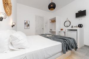 a white bedroom with a white bed and a tv at Naxos Beachwalk Rooms in Naxos Chora