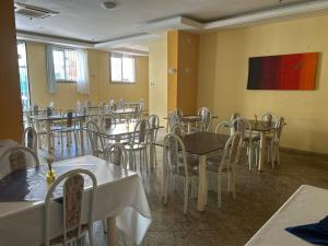 a dining room with tables and chairs and a painting at IDEAL HOTELS in Macaé