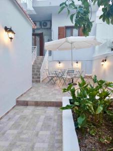 a patio with chairs and an umbrella and stairs at Utopia suites in Aegina Town