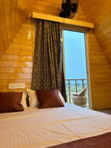 a bedroom with a bed with a large window at Buru Resort in Ghātsīla