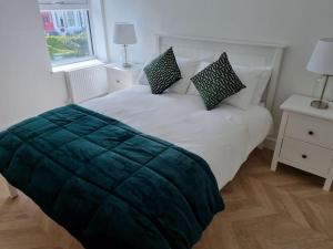 ein Schlafzimmer mit einem Bett mit einer grünen Decke darauf in der Unterkunft 16 Cambrian Court - New apartment with stunning sea views in Penmaen-mawr