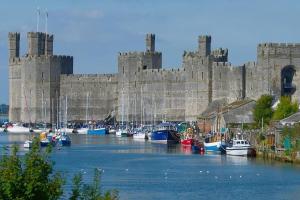 eine Reihe von Booten vor einem Schloss in der Unterkunft 16 Cambrian Court - New apartment with stunning sea views in Penmaen-mawr