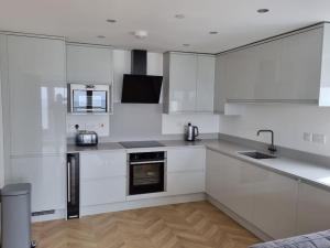 eine Küche mit weißen Schränken und einer Spüle in der Unterkunft 16 Cambrian Court - New apartment with stunning sea views in Penmaen-mawr