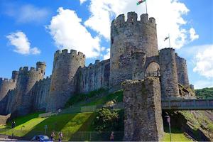 eine Burg auf einem Hügel mit einer Brücke in der Unterkunft 16 Cambrian Court - New apartment with stunning sea views in Penmaen-mawr + 12 Fotos