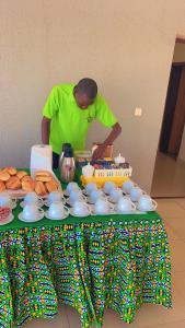 un hombre de pie junto a una mesa con un pastel en AG HOTEL Ouaga en Uagadugú