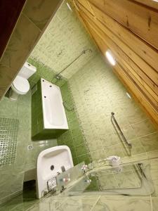 a green tiled bathroom with a toilet and a sink at MUNIS Hotel lyabi houz in Bukhara