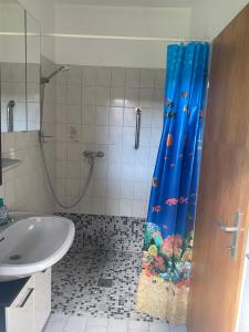 a bathroom with a shower with a blue shower curtain at Unter Den Eichen in Bötersen