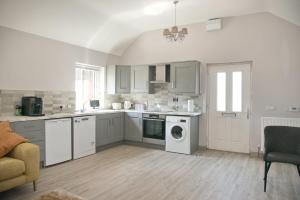 une cuisine avec des armoires blanches et une laveuse et une sécheuse dans l'établissement Creggan Deveskey Cottage, à Carrickmore
