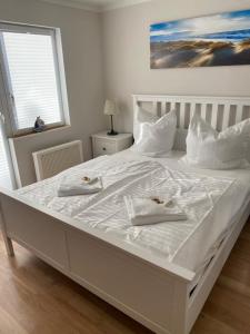 białe łóżko z dwoma białymi ręcznikami w obiekcie Fehmarnliebe w mieście Fehmarn