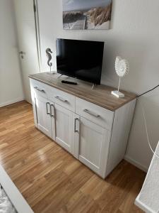 a white cabinet with a flat screen tv on top of it at Fehmarnliebe in Fehmarn