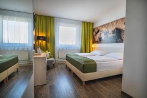 a hotel room with two beds and a desk at LifeHotel Vienna Airport in Fischamend Dorf