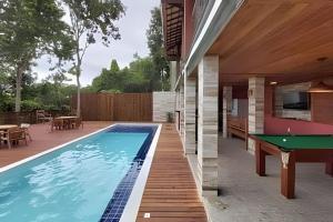 uma piscina com mesa de pingue-pongue ao lado de uma casa em Villa Maritaca Condo de 4 Casas de Alto Padrão Locação por Temporada em Arraial d'Ajuda