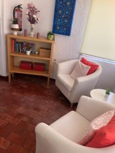 een woonkamer met 2 witte stoelen en een boekenplank bij Dona Ana - Residencial in Lagos