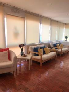 een woonkamer met banken, tafels en ramen bij Dona Ana Pensão Residencial in Lagos