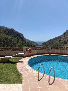 a swimming pool with a bridge and mountains in the background at CASA GASPAR, alojamiento rural con vistas al mar en paraje natural in Granada