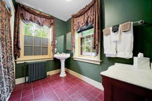 La salle de bains verte est pourvue d'un lavabo et d'une fenêtre. dans l'établissement Cromwell Manor Inn, à Cornwall-on-Hudson