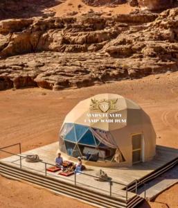 Ein Zelt in der Wüste, in dem Leute sitzen. in der Unterkunft MARS LUXURY CAMP WADi RUM in Wadi Rum