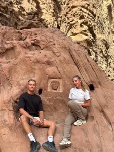 two people sitting on top of a rock formation at Hashem desert camp in Wadi Rum